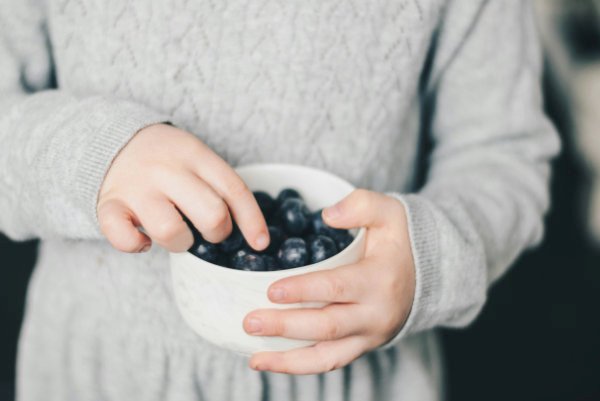Child eating blueberries at school.